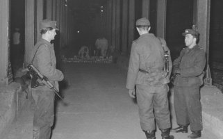 Grenzsoldaten bewachen Maurer, die eine Sperrmauer zwischen den Berliner U-Bahnhöfen Heinrich-Heine-Straße und Moritzplatz errichten, 15. Februar 1963.