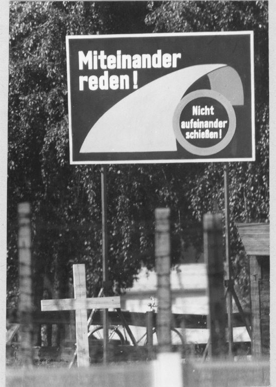 Werner Kühl, shot dead at the Berlin Wall: Memorial cross in front of a poster of the Studio at the Barbed Wire in Berlin-Britz [July 1971]