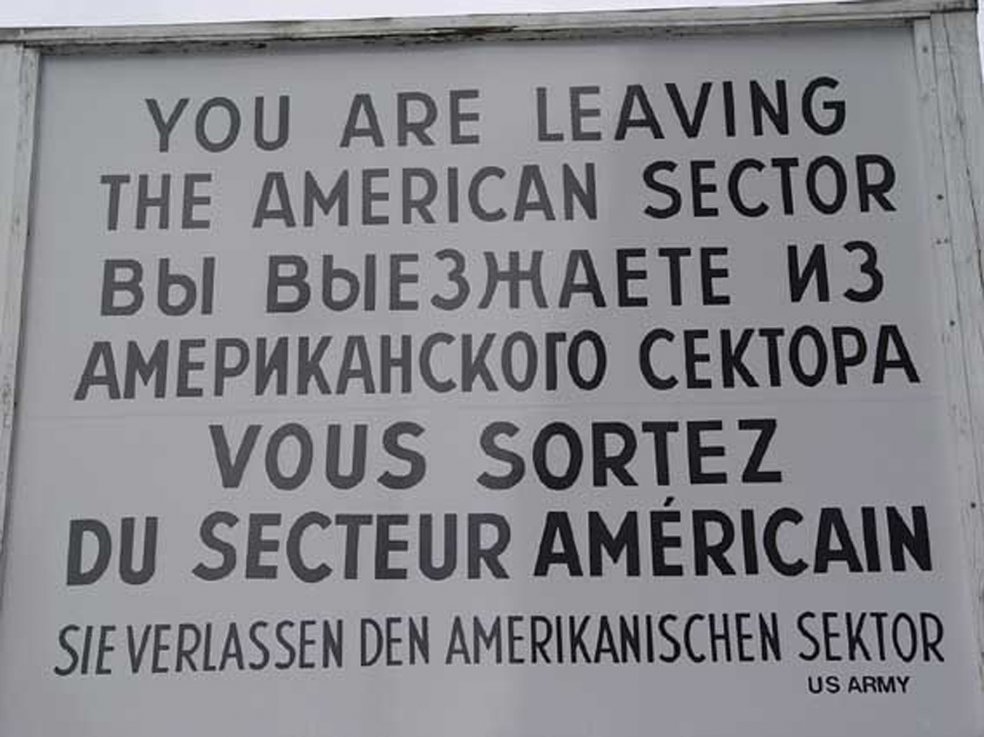 Auf einem Schild steht in englischer, russischer, französischer und deutscher Sprache, Sie verlassen den amerikanischen Sektor. US Army.