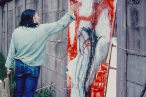 Elsner steht auf einem Haufen herausgebrochener Mauerzeile. Neben ihm in der Mauerl&uuml;cke ist sein abstraktes Bild eingesetzt, das er mit einer Spr&uuml;hpistole mit roter Farbe weiter bearbeitet.