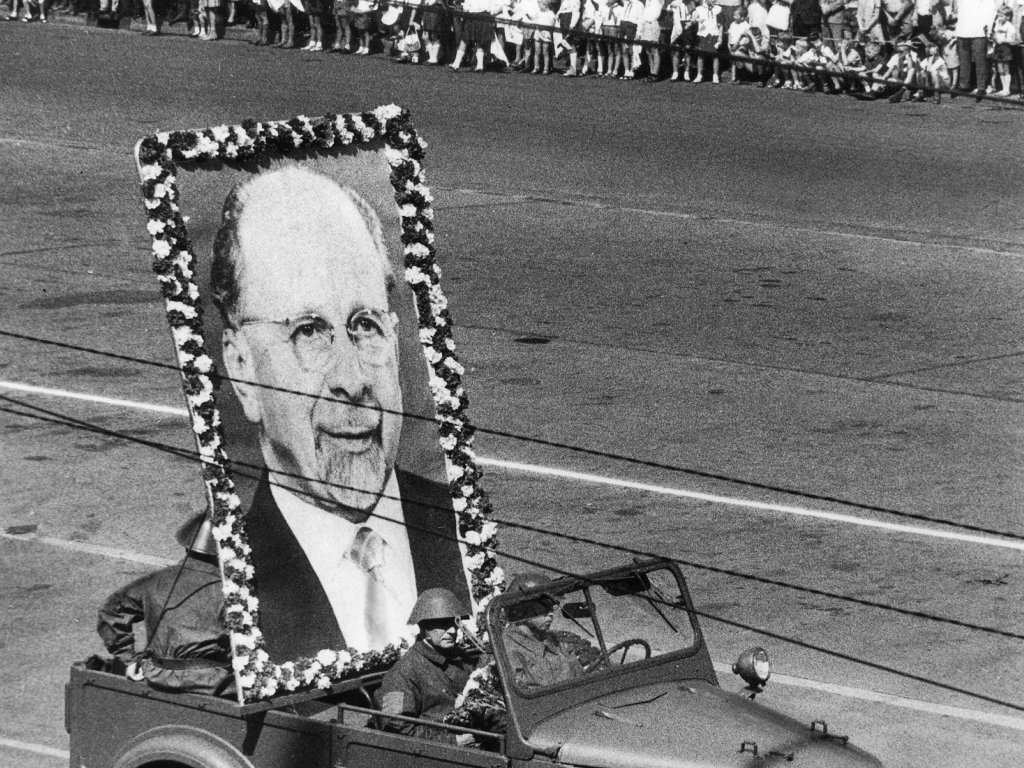 1966: Am fünften Jahrestag des „Antifaschistischen Schutzwalls“ wird die Mauer in der DDR offiziell mit Kampfgruppen-Paraden gefeiert. Der Zug führt durch die Straße Unter den Linden, vorweg ein Wagen mit dem überlebensgroßen Porträt des Staatsratsvorsitzenden Walter Ulbricht.