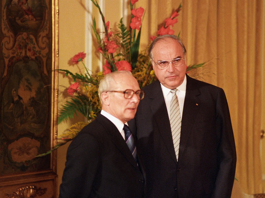 Honecker steht links neben Kohl. Im Hintergrund ein golden gerahmtes Bild und ein großer Blumenstrauß.