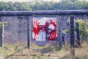 Die Mauer ist aus einigen Metern Entfernung frontal aufgenommen. Im Zentrum ist das abstrakte Bild in der Mauerl&uuml;cke. Links neben dem Bild ist Stephan Elsner, der dabei ist, wegzulaufen.