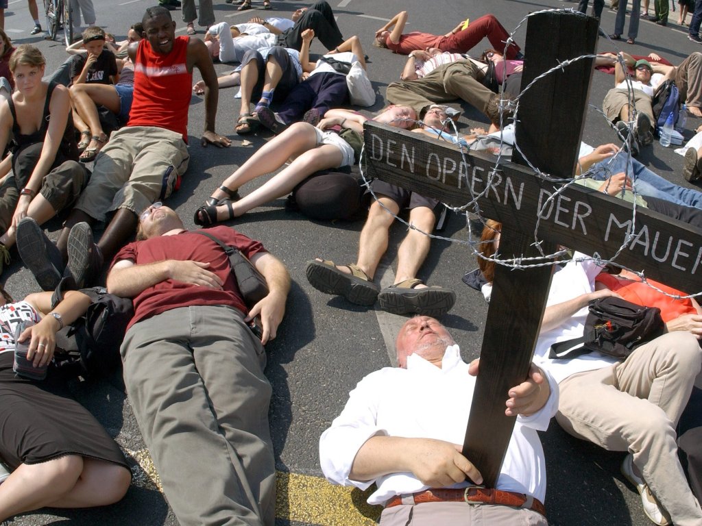 2003: Am 42. Jahrestag des Mauerbaus gedenken etwa 80 Menschen auf der Straßenkreuzung am Potsdamer Platz liegend der Opfer der Berliner Mauer. Der Veranstalter hatte mit mehreren Hundert gerechnet. Der Regierende Bürgermeister Klaus Wowereit äußert an diesem Jahrestag die Befürchtung, dass die Erinnerung an die Mauer verblasse: „Wir müssen aufpassen, dass die DDR nicht Kult wird“.